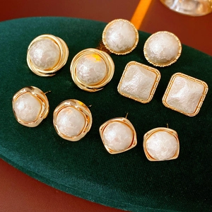 Detail view of five pairs of vintage gold-plated round earrings on a green velvet pad