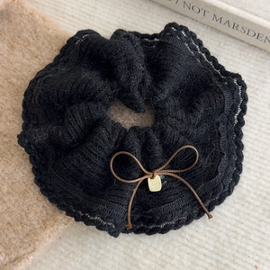 Close-up of black knitted scrunchie with wave lace edge and brown bow accent