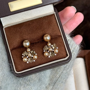 Detail of vintage flower earrings featuring brown pearls and crystals on a velvet box