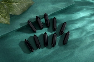 Detailed set of ten polished black obsidian hexagonal double-pointed crystal pillars