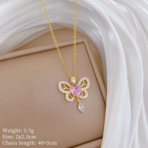 Detail of gold butterfly necklace featuring pink heart stone and dangling zircon teardrop