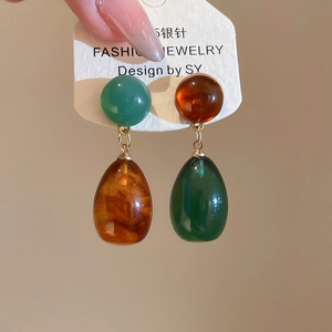Detail of asymmetric resin teardrop earrings with S925 silver needles and amber beads