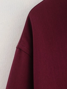 Macro shot of stitching details and twill fabric texture on burgundy jacket shoulder