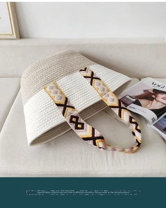 Detail of woven cotton rope bag with geometric pattern strap on a grey sofa