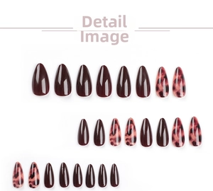Detail view of almond shape press-on nails with burgundy finish and leopard patterns