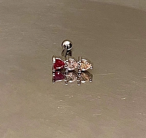 Macro view of steel barbell stud with three heart-shaped colorful zircon stones