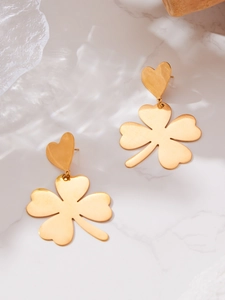 Detailed shot of gold clover and heart drop earrings on a luxury marble background