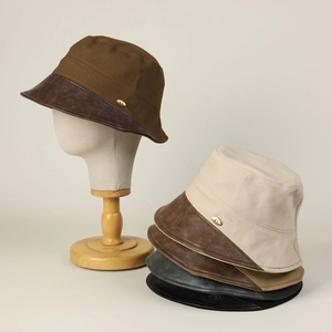 Detail of cotton canvas bucket hat with leather brim and metallic emblem accent