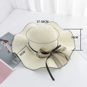 Detail of straw hat with wave brim and black polka dot mesh bow decoration