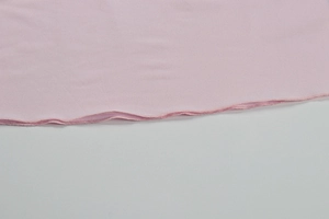 Close-up of pink dress with detailed lettuce edge hem and stitching on knit fabric