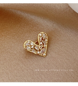 Macro detail of gold heart brooch with sparkling zircons on elegant champagne fabric