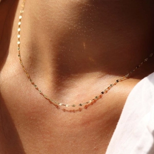Detail of minimalist gold-plated silver chain necklace on skin showing subtle texture