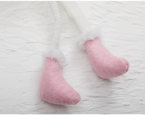 Detail of pink wool felt boots with white faux fur trim and knitted legs for Christmas
