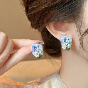 Detailed macro view of vintage oil painting style earrings with purple and green enamel