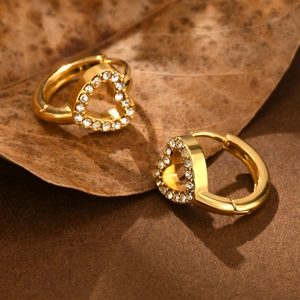 Macro shot of gold-plated heart-shaped hoop earrings with sparkling white crystals