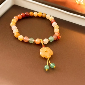 Detail of colorful beaded bracelet with flower pendant and green tassel on dark stand