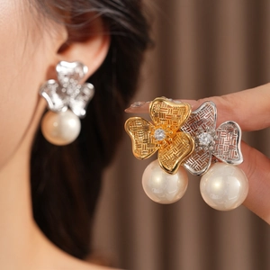 Close-up of vintage flower earrings with sparkling zircon centers and elegant pearl drops