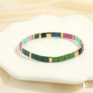 Detailed shot of multi-colored Tila beads with golden accents on a shell-textured plate