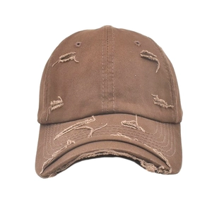 Close-up of brown distressed cotton baseball cap with vintage frayed hole details