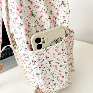 Detail of floral canvas backpack side pocket with a phone in a soft natural light