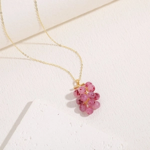Close-up of a beaded grape pendant necklace with translucent purple beads and gold chain