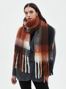 Detail of red-brown thick plaid loop yarn scarf with fringe tassels on a model