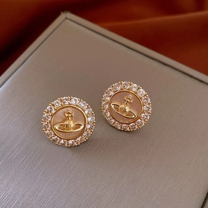 Détail de boucles d'oreilles rondes vintage avec relief Saturne doré et zircons blancs