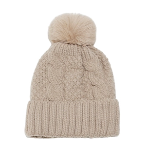 Close-up of cable knit patterns and fluffy pom-pom on an apricot winter beanie hat