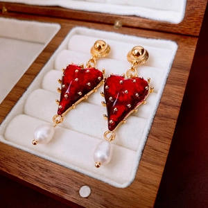 Macro shot of vintage heart earrings with baroque pearls in a velvet jewelry box