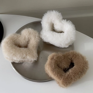 Three plush heart-shaped hair claws in white beige and brown on a metal tray