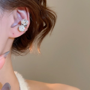 Detail of silver ear bone clips with clear round gemstones worn on a model's ear