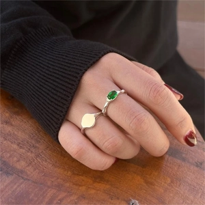 Minimalist 925 sterling silver ring featuring a green oval gemstone on wood background
