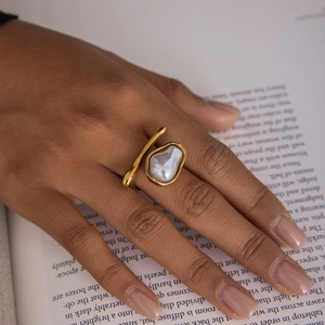 Close-up of 18K gold stainless steel baroque pearl ring worn by a model over a book