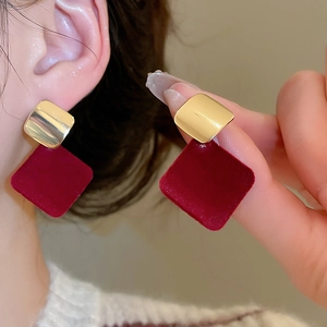 Gros plan de boucles d'oreilles carrées rouges floquées et dorées sur une femme