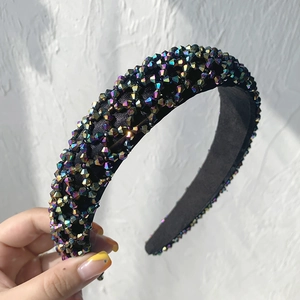 Detail of black wide headband with iridescent multifaceted beads held by a hand