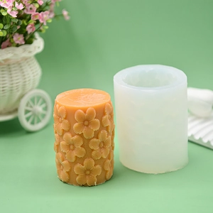 Detail of cylindrical silicone mold and finished orange embossed floral candle