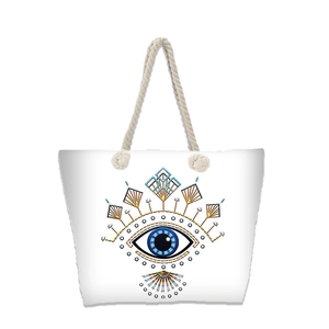 Detailed view of white canvas beach tote with blue evil eye pattern and rope handles