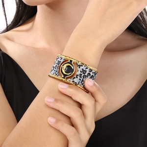 Detailed shot of a wide gold cuff bracelet featuring leopard print and a crescent moon icon