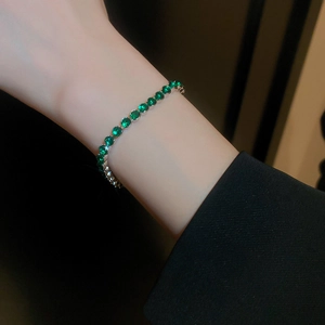Détail d'un bracelet en zircon vert émeraude porté au poignet avec monture argentée