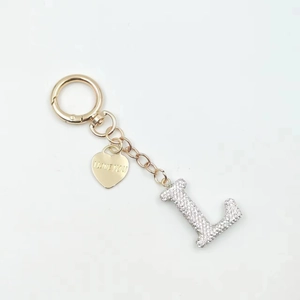 Close-up of golden letter L keychain pendant with rhinestones and heart tag