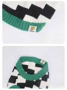 Detailed view of dog sweater with green ribbed hem and decorative smile woven label