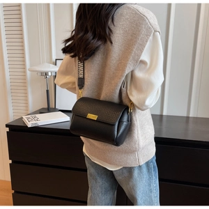 Detail of minimalist black crossbody bag with stylish houndstooth wide strap and gold hardware