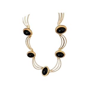 Vintage gold layered necklace with oval black gemstones on a minimalist white background
