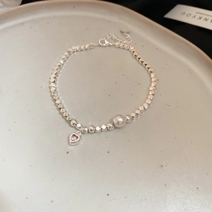 Dettaglio del bracciale di perline argento con ciondolo a cuore, zircone rosa e perla
