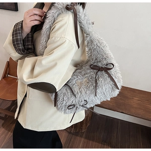 Dettaglio della borsa a tracolla in peluche grigio con fiocchi in pelle marrone e metallo
