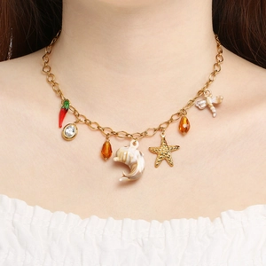 Gros plan d'un collier doré avec pendentifs coquillage et étoile de mer sur un mannequin