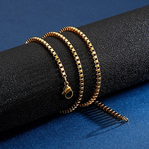 Detailed close-up of golden stainless steel box chain with lobster clasp on black stand