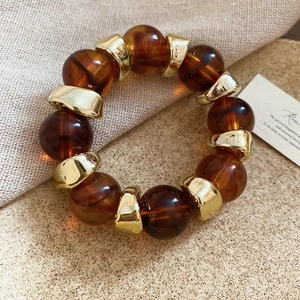 Close-up of amber acrylic resin beads paired with irregular gold metal spacers on a bracelet