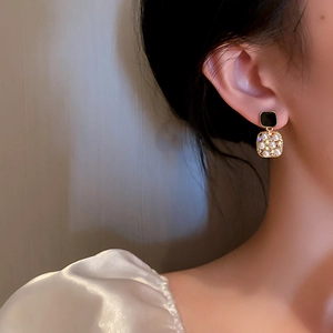 Detail of elegant gold square earrings with faux pearls on model for vintage luxury look