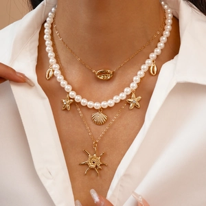 Close-up of layered necklace set featuring faux pearls, starfish and seashell charms